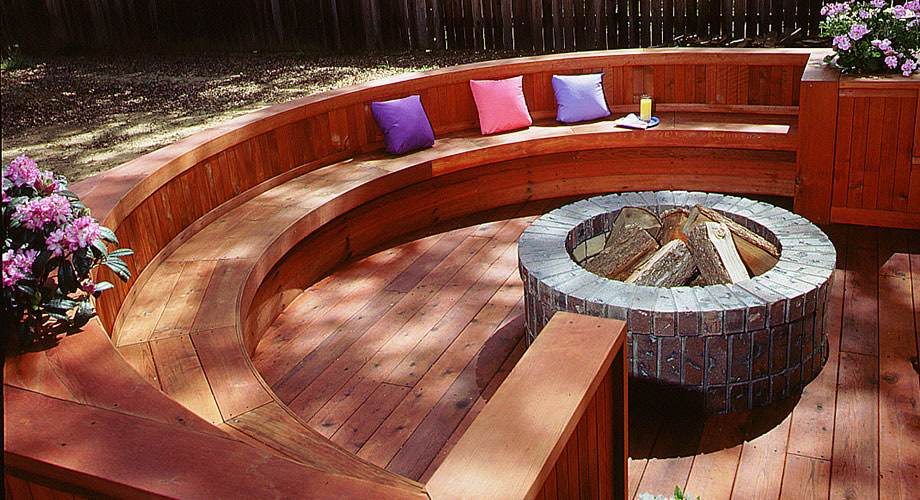 Outdoor wood deck with curved built-in seating around a fire pit