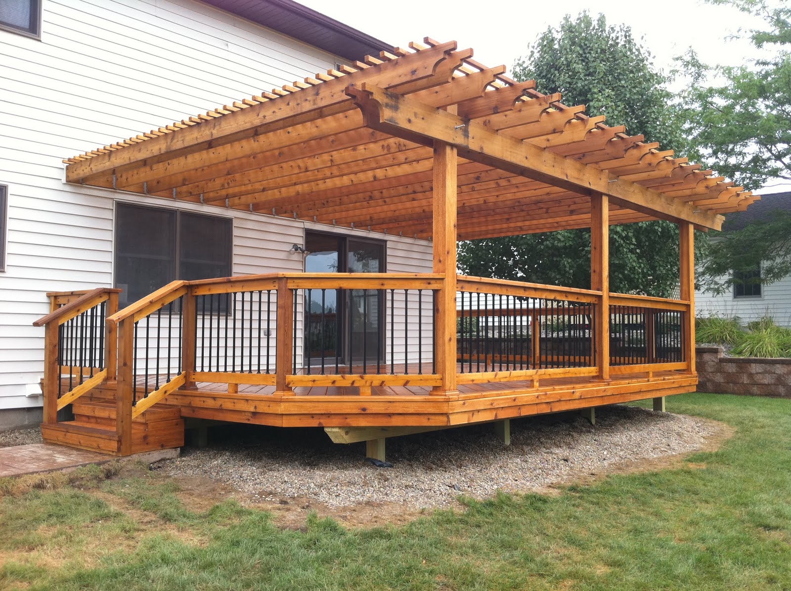 Finished wood deck with pergola, broad stairs and black metal balusters